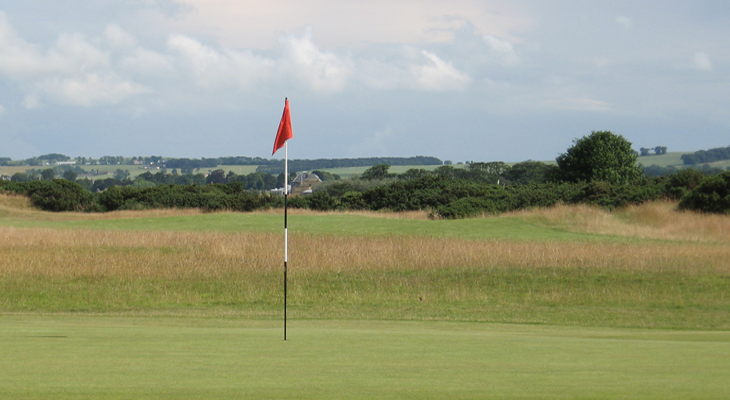 Red flag stand in a golf course field