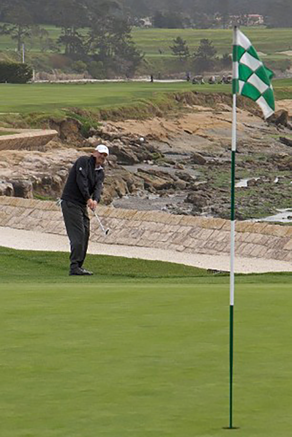 A golfer positions his ball on the green